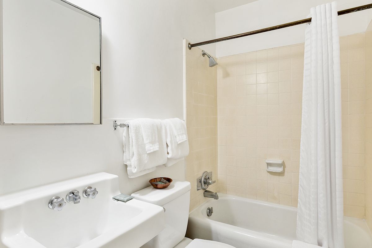 A clean bathroom with a bathtub, shower curtain, towel rack, and a white sink countertop.