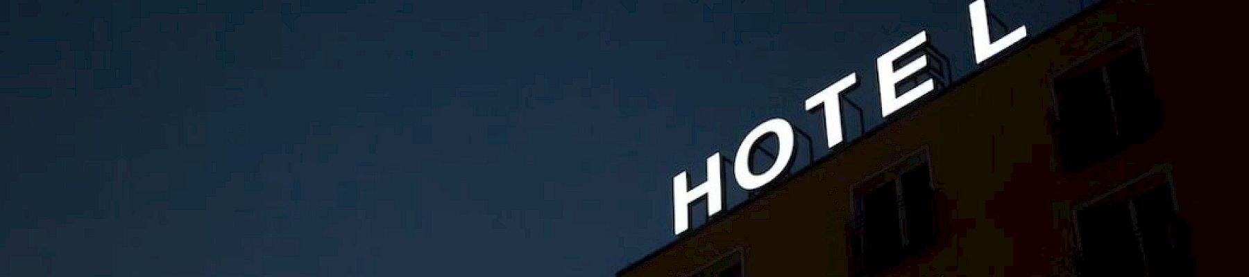 A building at night with the word "HOTEL" illuminated at the top against a dark sky.