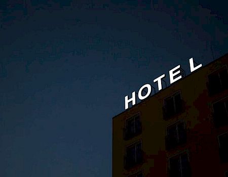 A building at night with the word "HOTEL" illuminated at the top against a dark sky.