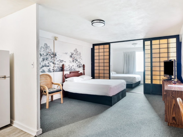 The image shows a room with a bed, chair, refrigerator, TV, and decorative wall panels, featuring a simple and clean design.